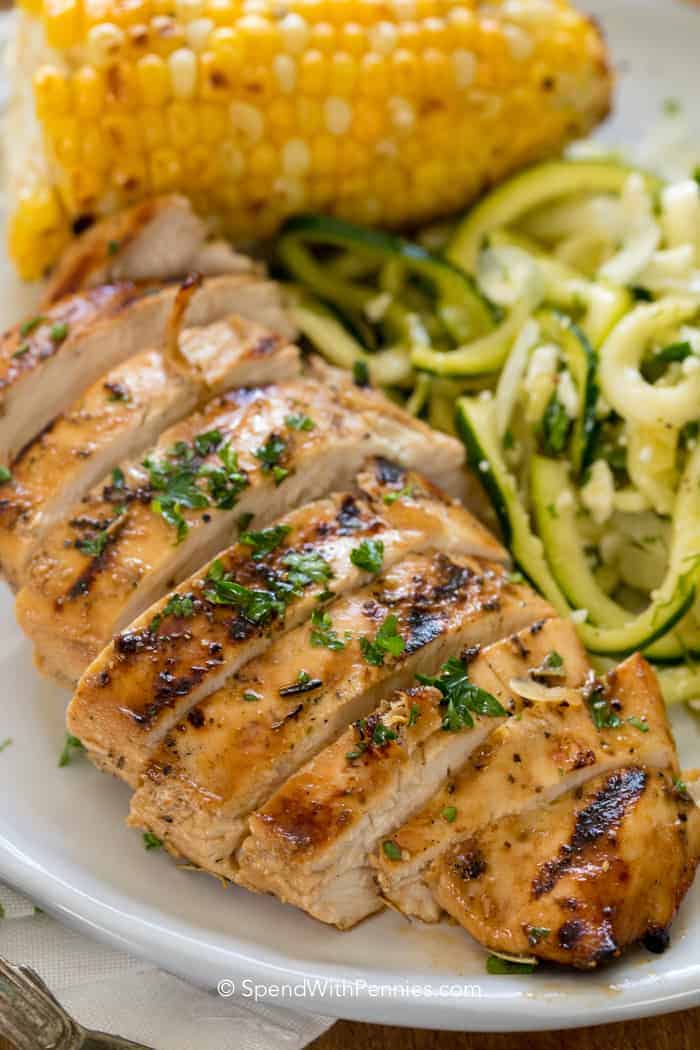 Marinated grilled chicken on a plate with zoodles and corn