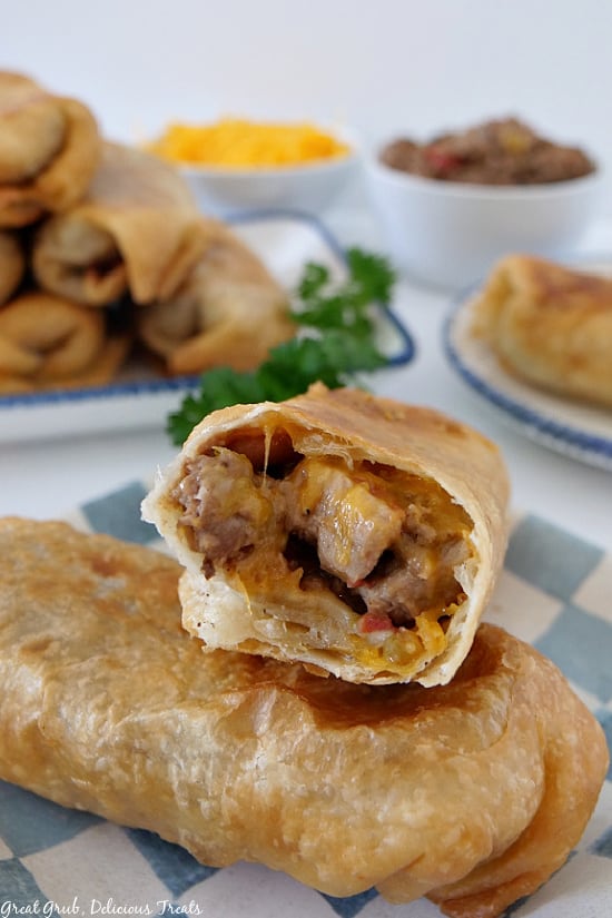 Two fried burritos on a white and blue checkered plate with a burrito with a burrito filling.