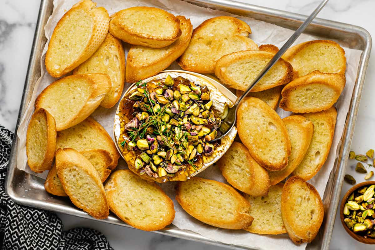 Baked Brie on a baking tray covered with fig jam and pistachios