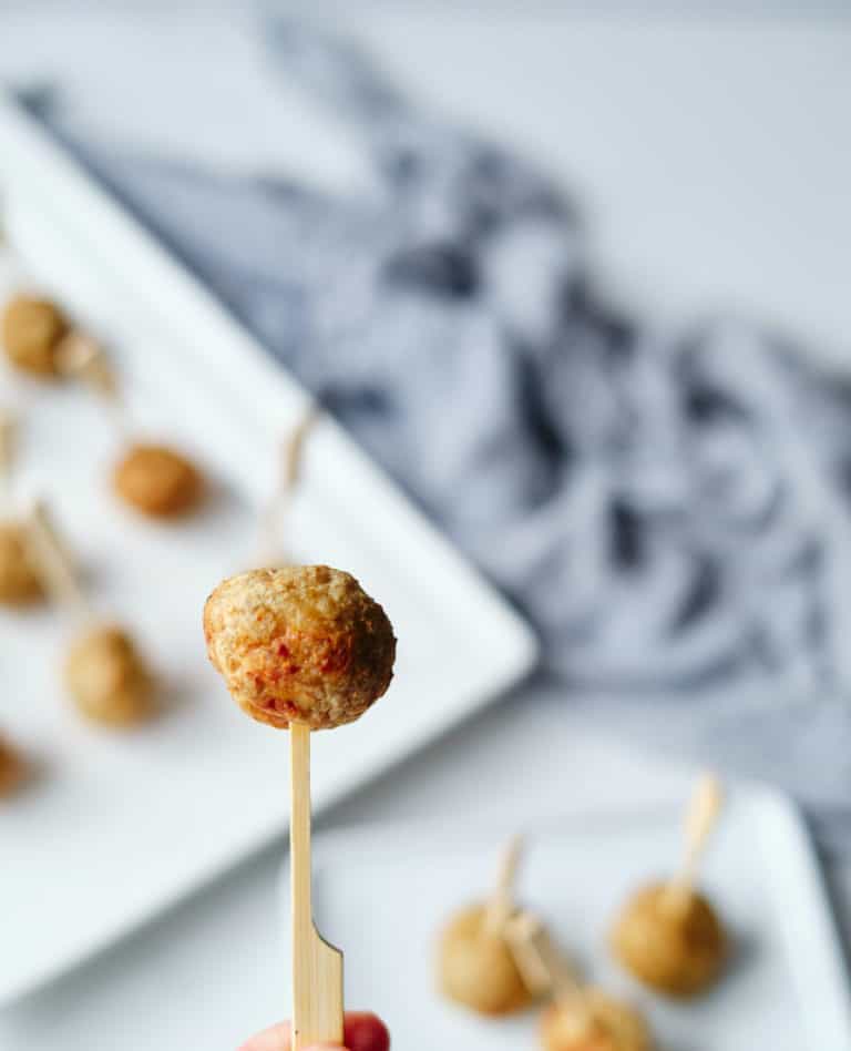 6 of the finished product of the meatball frozen air fryer with toothpicks served on a white plate