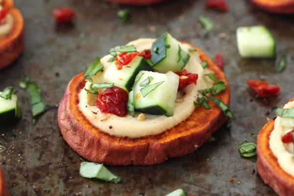 Bake round sweet potatoes with hummus, cucumbers, and sun-dried tomatoes.