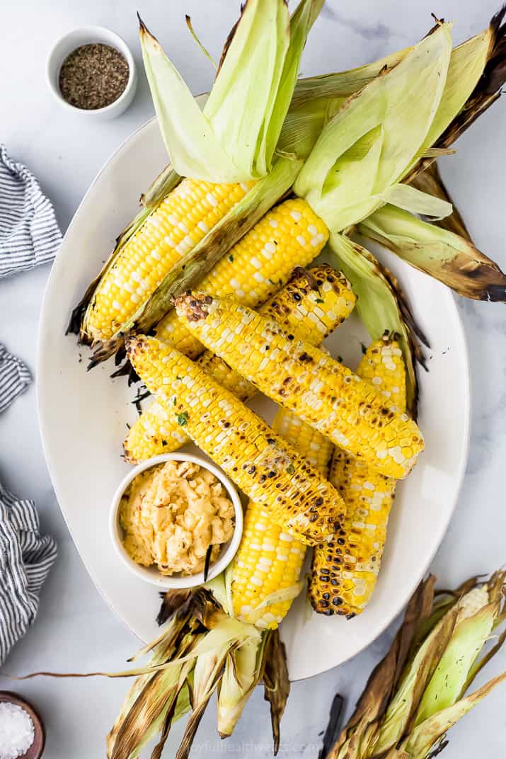 a plate full of roasted corn on the cob and honey chipotle butter