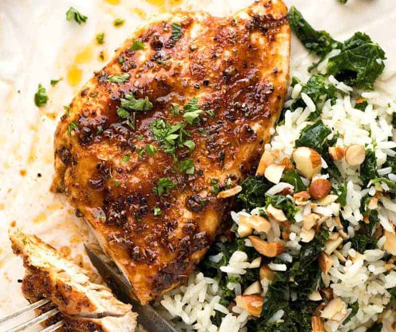 Oven-roasted chicken breast on a white plate with kale and garlic butter rice