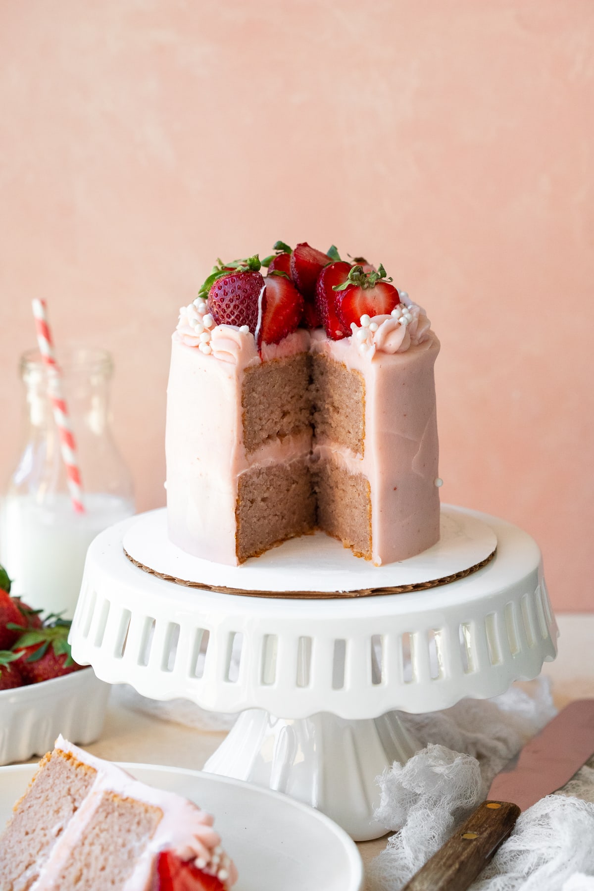 Center cutout of cake on white cake stand on pink background.