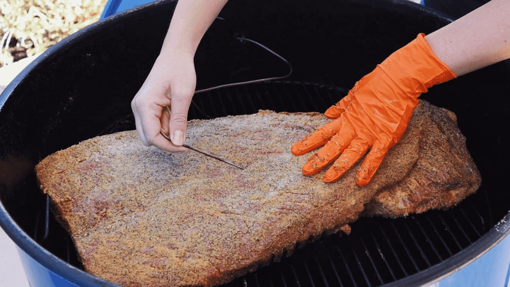 Insert the temperature probe into the seasoned beef brisket.