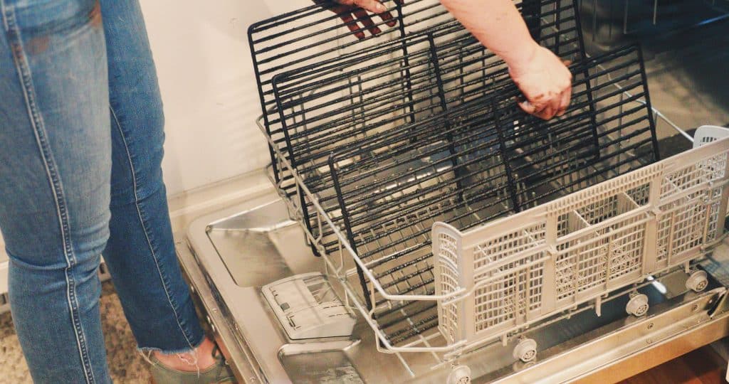 Woman putting grill in dishwasher.