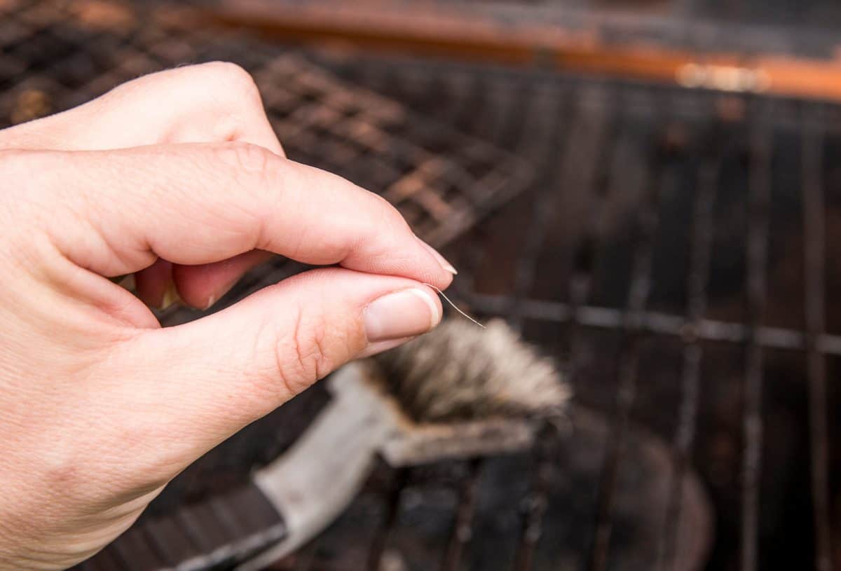 A person holding a wire from a grill brush