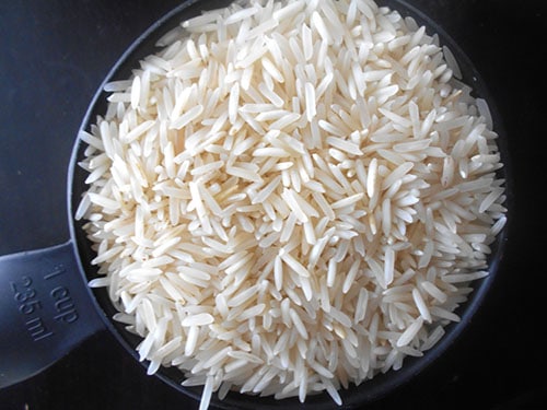 Top view of uncooked basmati rice in 1 cup measuring cup