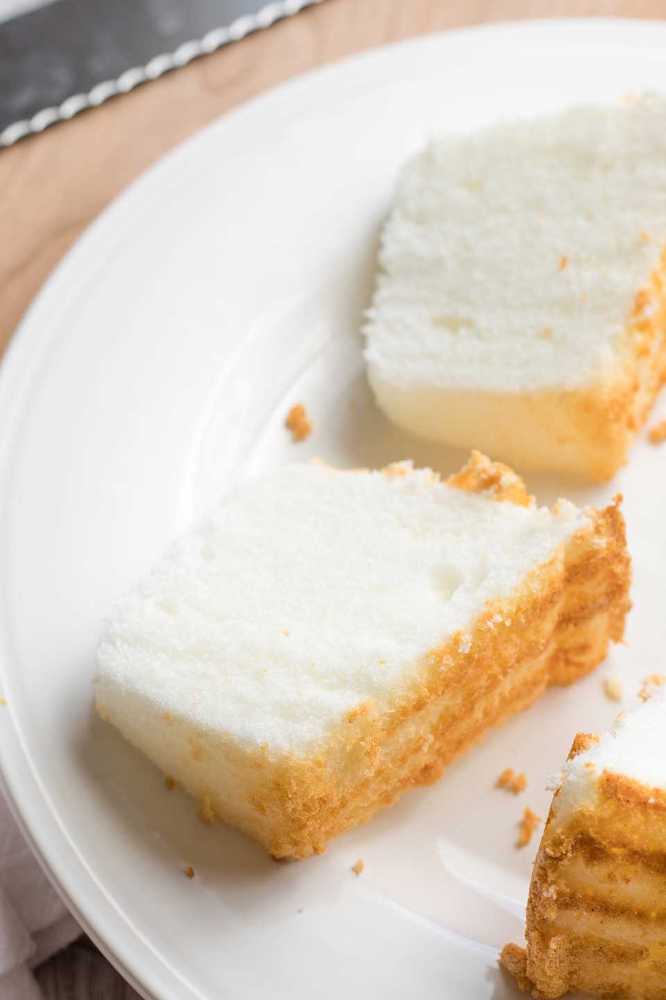 Photo of a slice of cake, lying on its side on a white plate, with other slices of cake cut nearby on the plate.