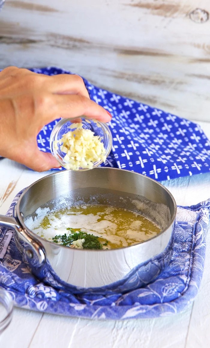 Horseradish cream sauce on a golden spoon over a bowl of horseradish sauce on a blue background.