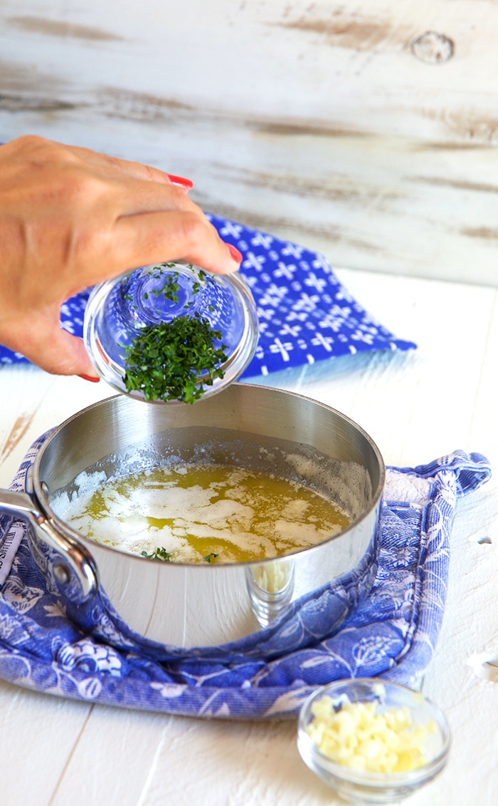 Garlic butter sauce in a pan over a blue and white pothole.