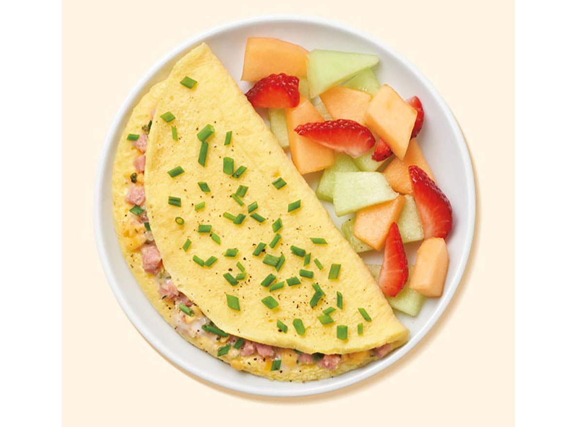 turkey ham and cheese omelette plated with chopped fruit