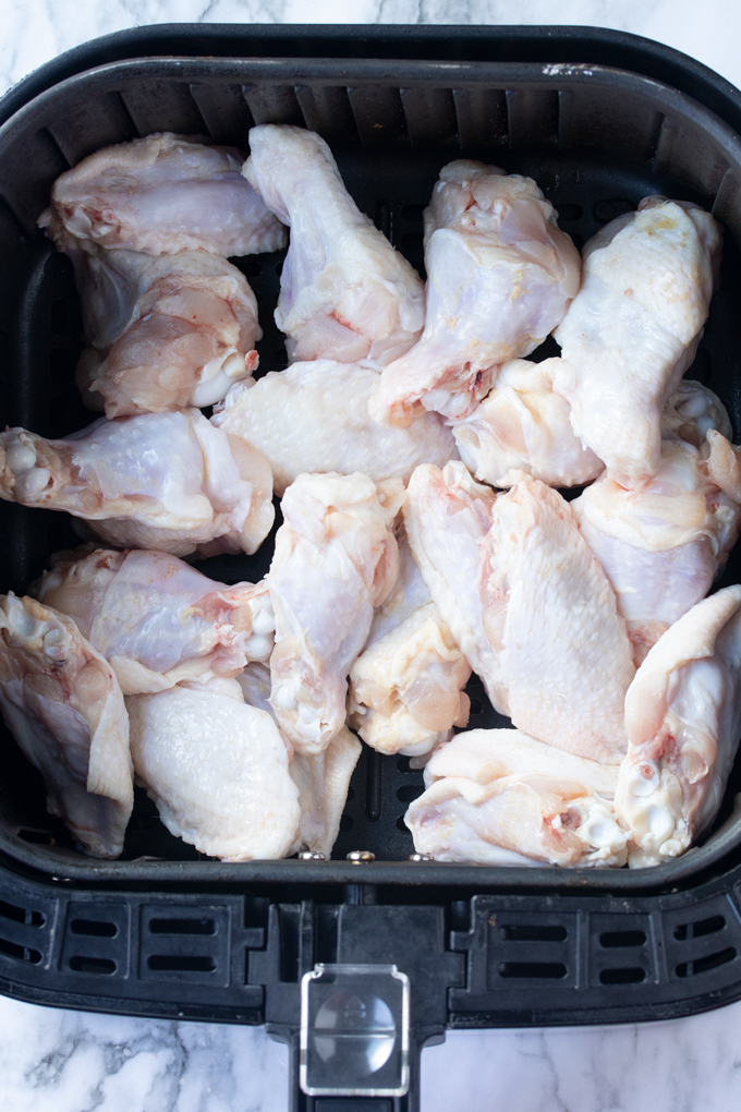 Raw chicken wings in the air fryer basket