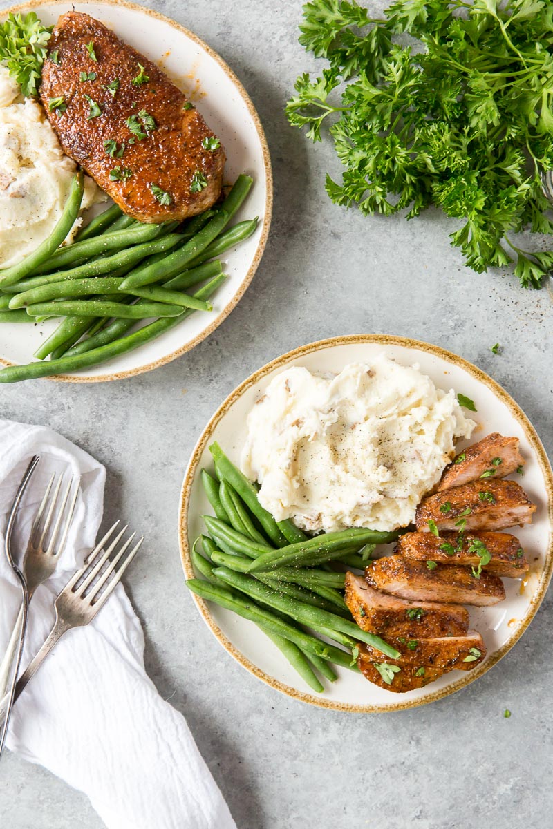 two plates with meat, mashed potatoes and green beans