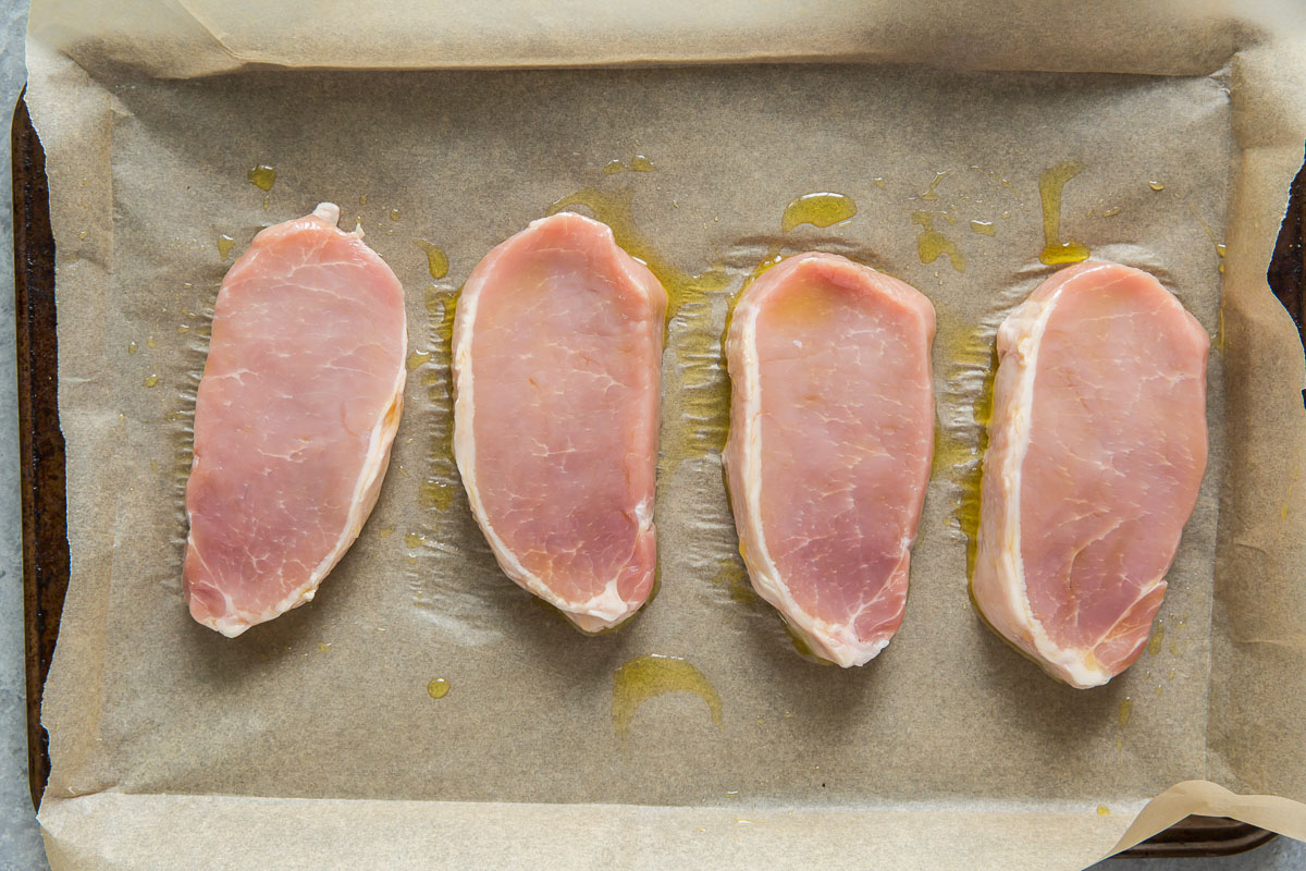Prepare uncooked pork chops with olive oil on a baking sheet