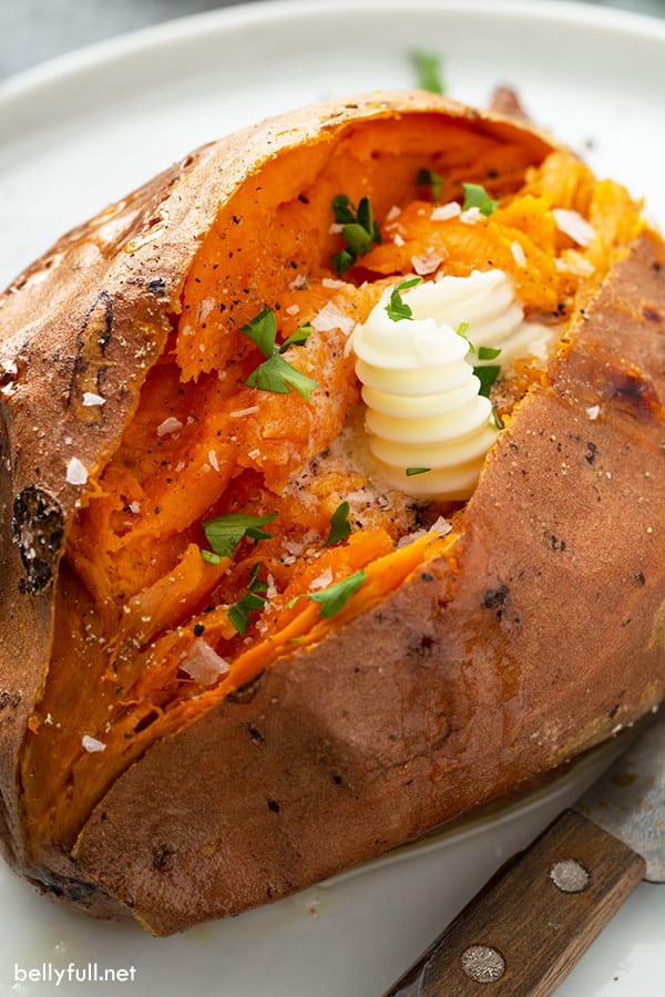 Close-up of baked sweet potato with melted butter and sprinkled with chopped parsley