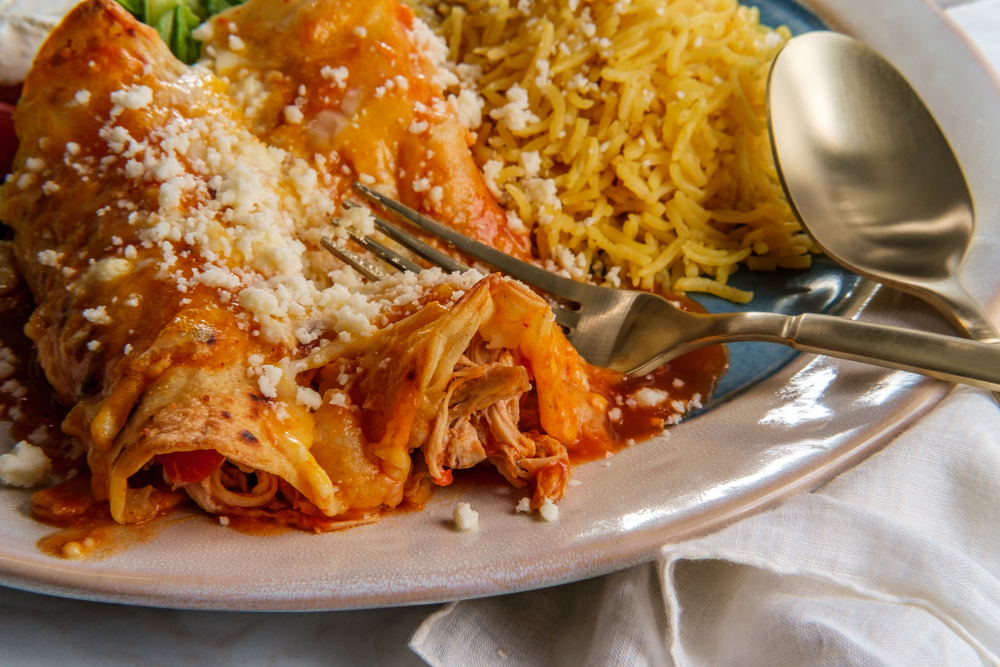 enchiladas on a plate with spoon and fork