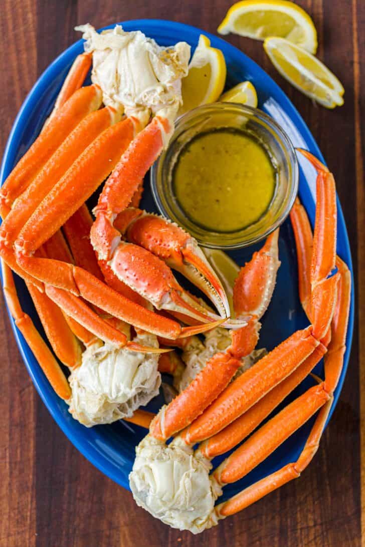 Crab legs cooked on a green plate served with dipping sauce