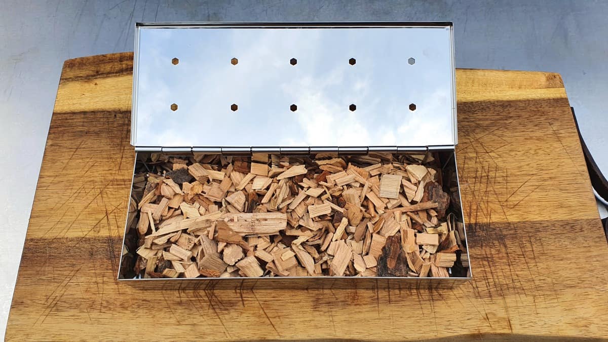 smoking box full of wood chips, sitting on a cutting board