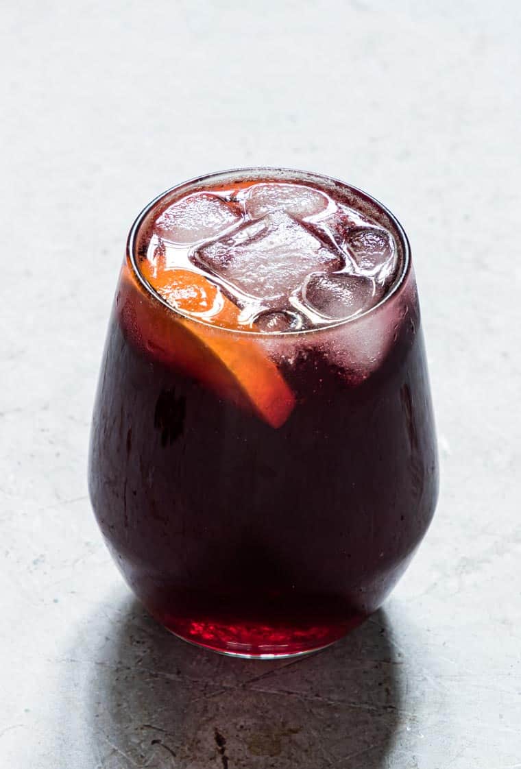 Jamaican Sorrel is served in a glass with ice cubes and oranges