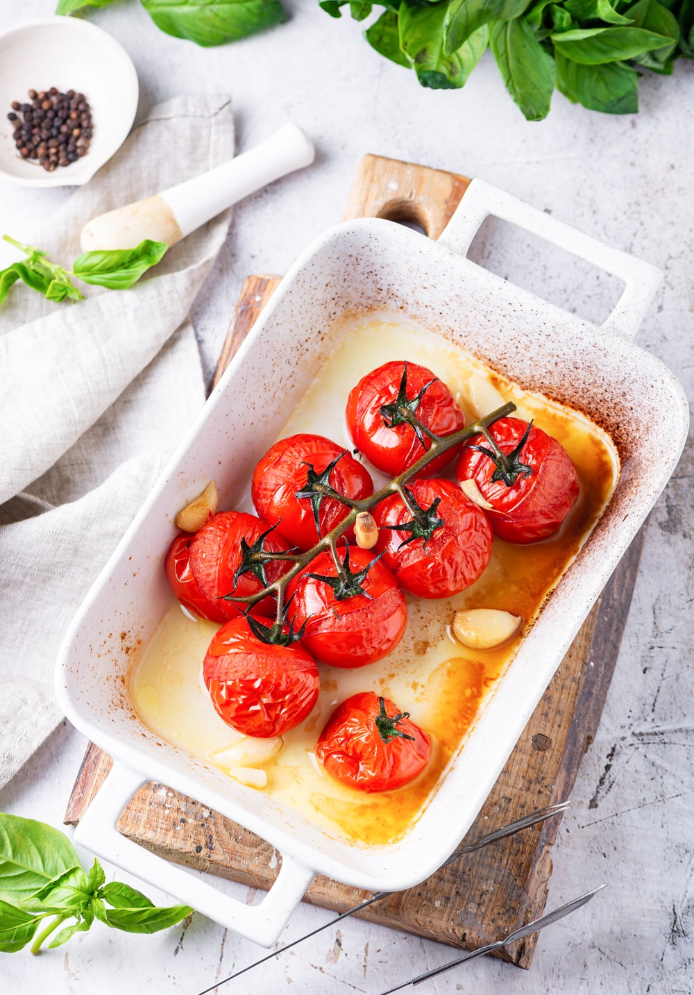 Tomato and garlic cooked in a white baking dish.