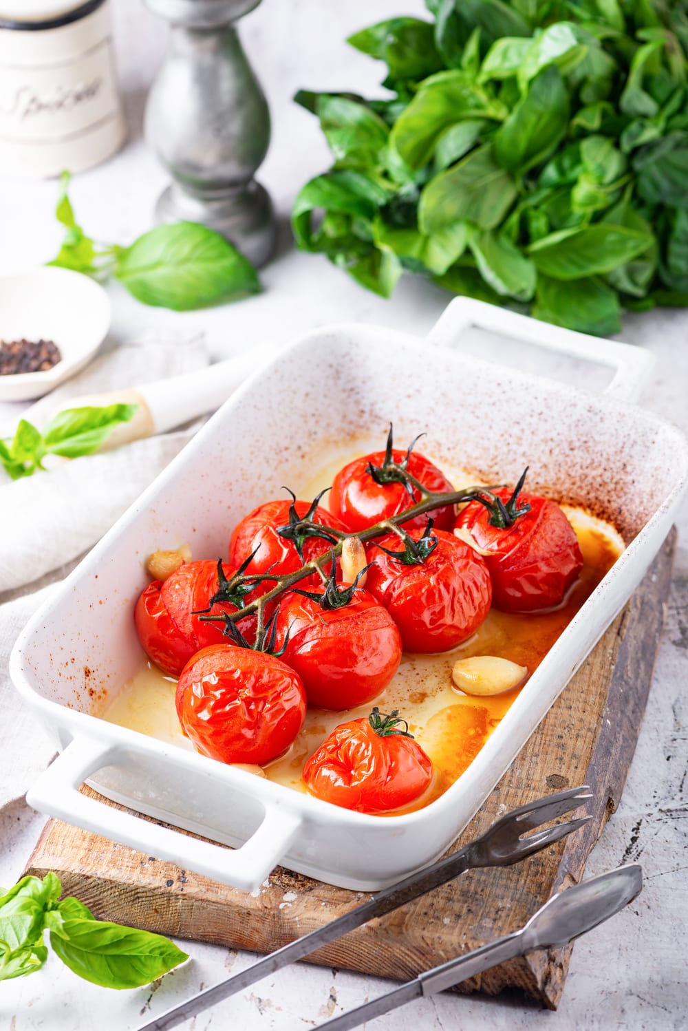 Tomato and garlic were cooked in a white baking dish with basil leaves behind.