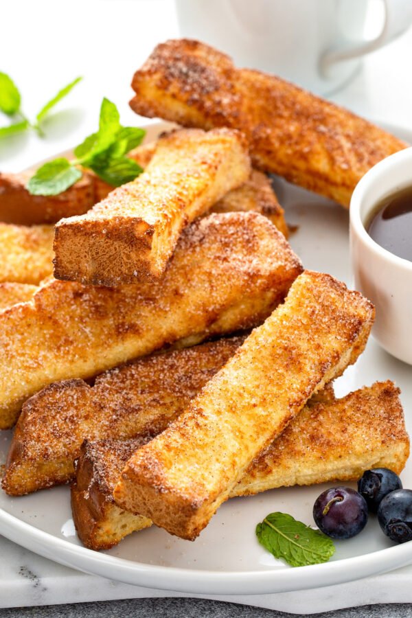 A stack of French toast lies on a white plate.