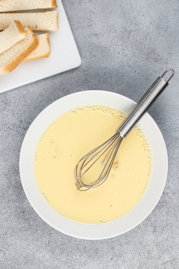Using a whisk, whisk together a bowl of milk, eggs, and vanilla.