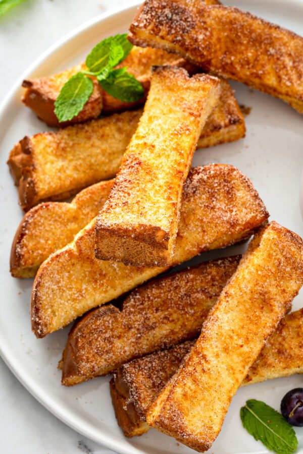 French toast sticks arranged on a round white plate.