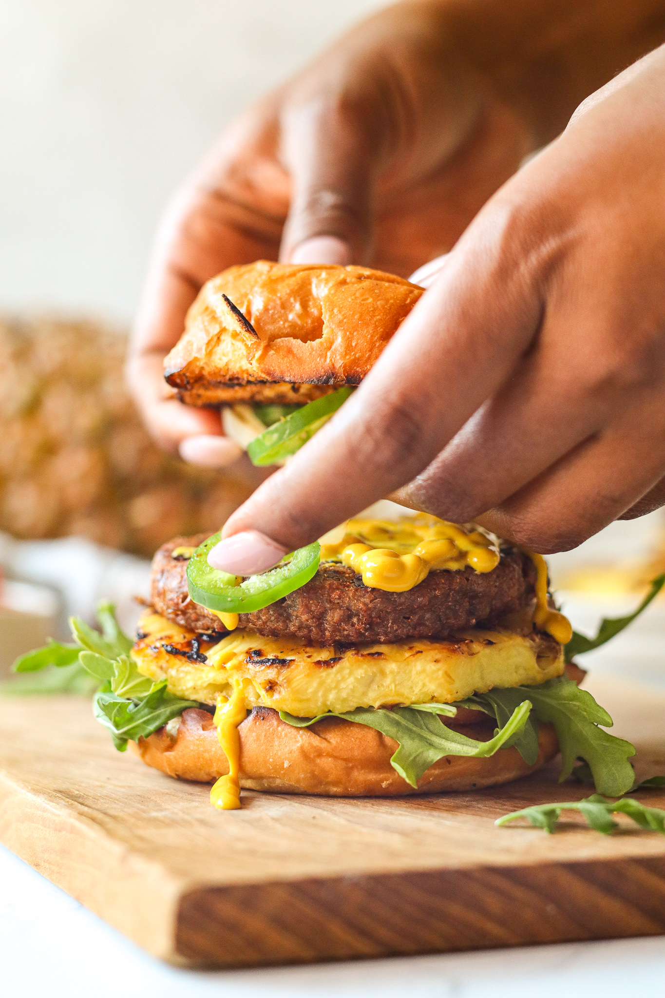 Assemble the Beyond Burger with favorite toppings: mustard, jalapeno, pineapple, arugula