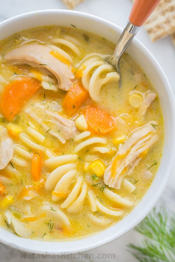 Creamy chicken soup garnished with dill in a bowl with a spoon