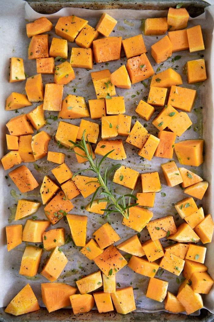 Pumpkin cubes on a baking tray coated with oil and herbs