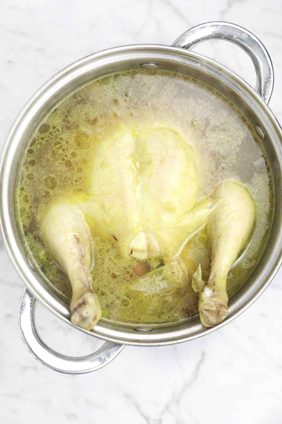 Put the whole chicken in the pot of broth.