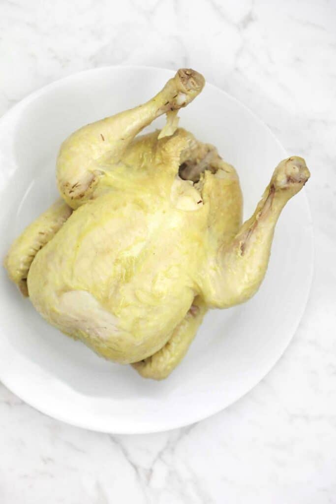 whole boiled chicken on a white plate.