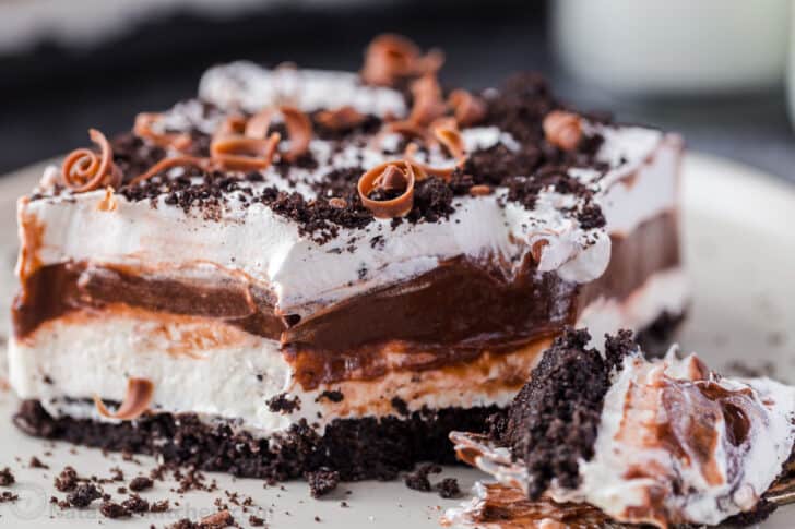 A slice of chocolate lasagna on a white plate covered with chocolate chips.