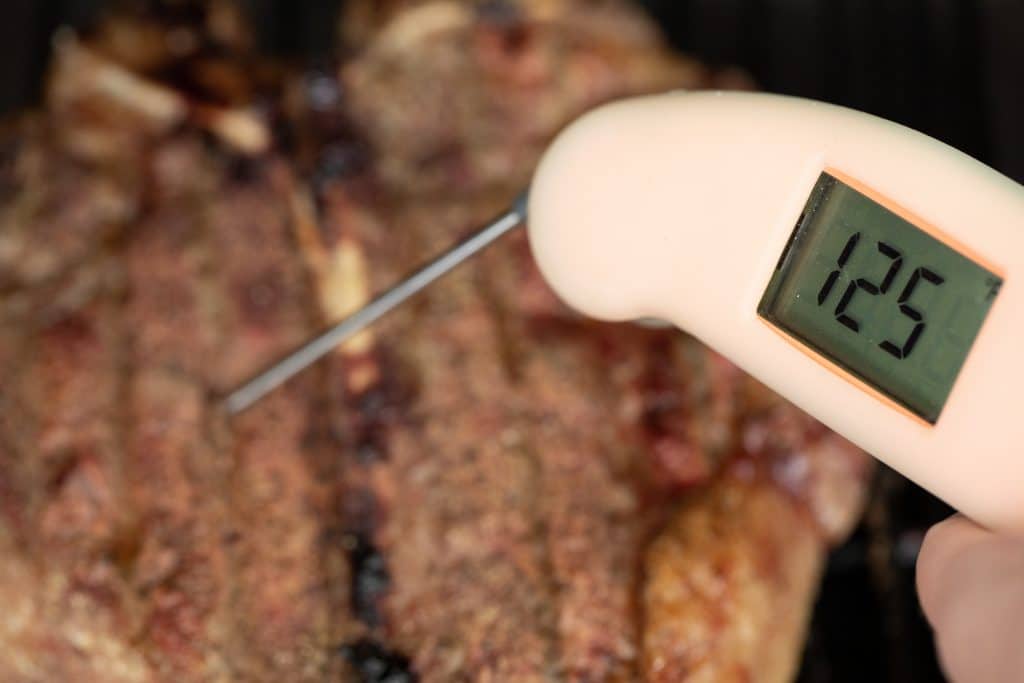 Close-up of thermometer plugged into porterhouse steak reading 125 degrees F.