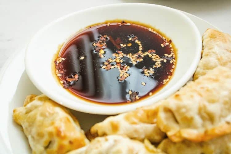 Close-up of dumpling sauce in a white bowl with sesame seeds