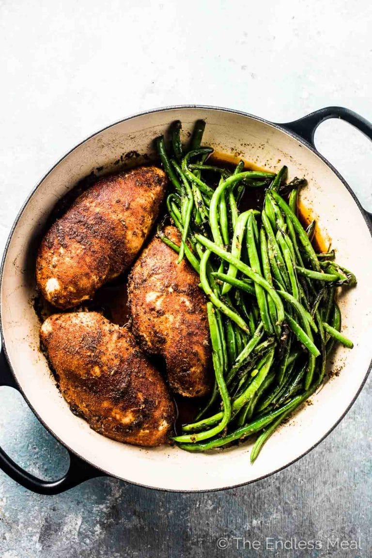 3 juicy oven-roasted chicken breasts in a pan with green beans on the side.
