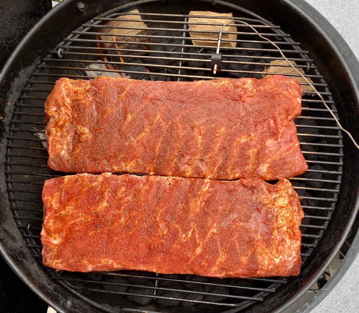 Overhead view showing where to position two racks St Louis spare ribs that are to be smoked on a charcoal grill.