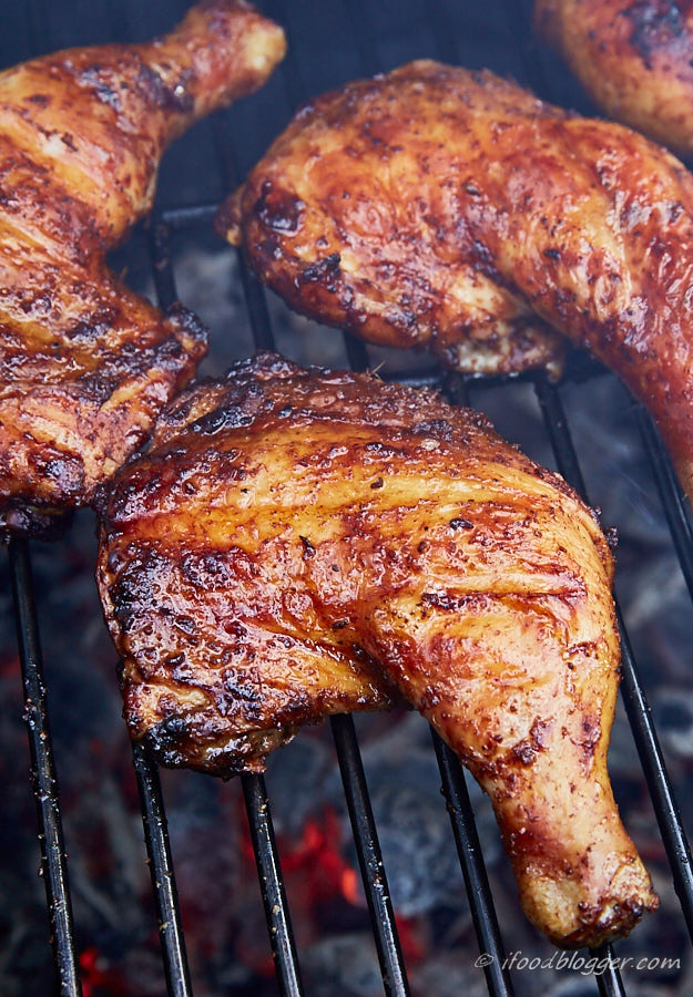 Deep golden browned chicken legs on a charcoal grill.