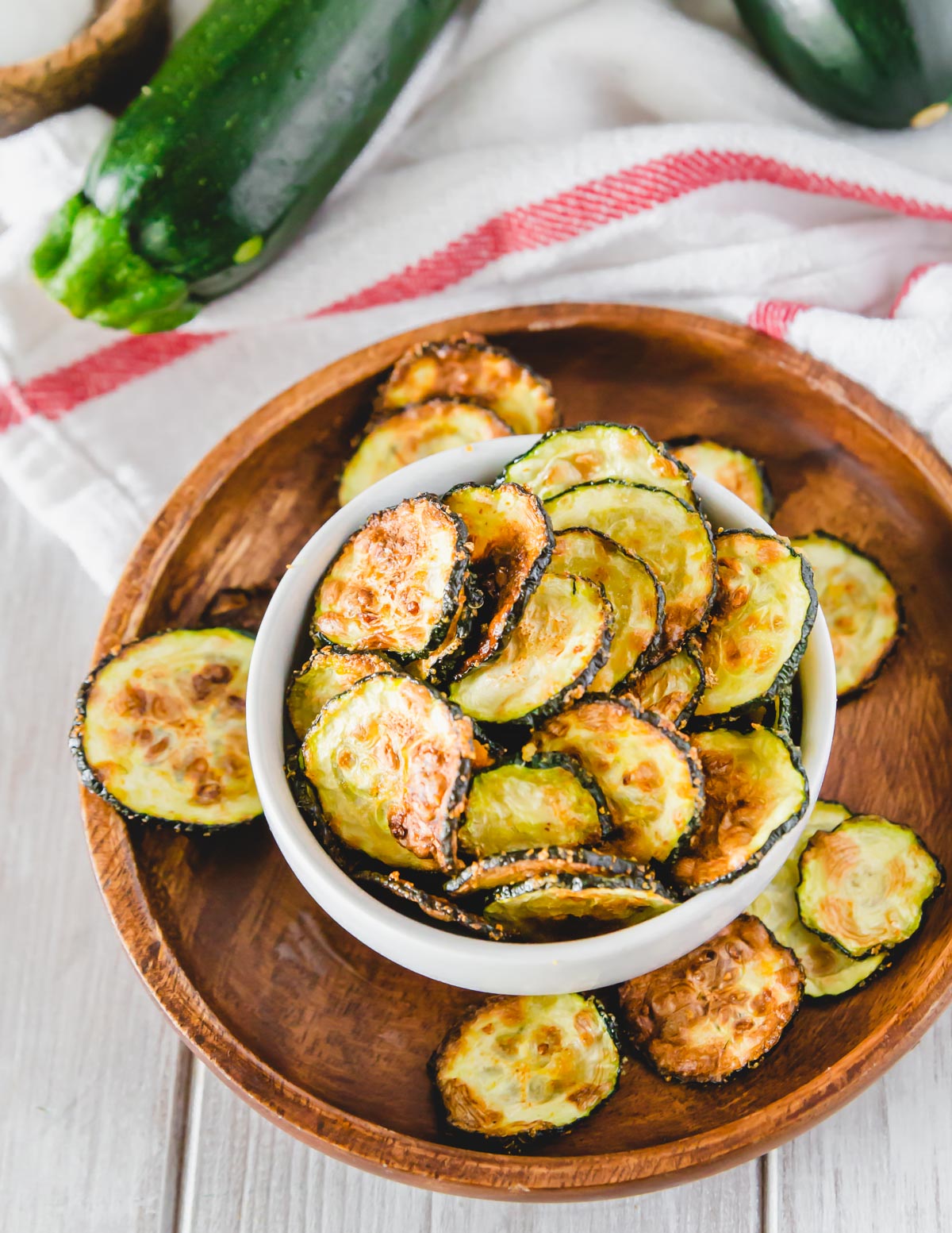 Breadless zucchini chip air fryer in a serving bowl on a plate.