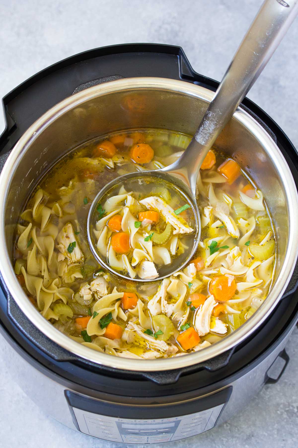 Chicken noodle soup in an instant pot with a ladle