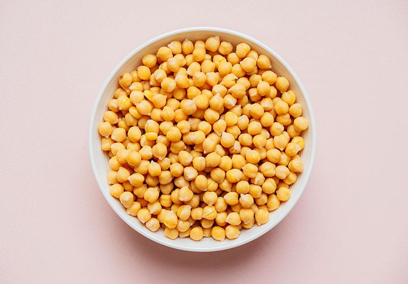 Uncooked chickpeas in a bowl on a beige background