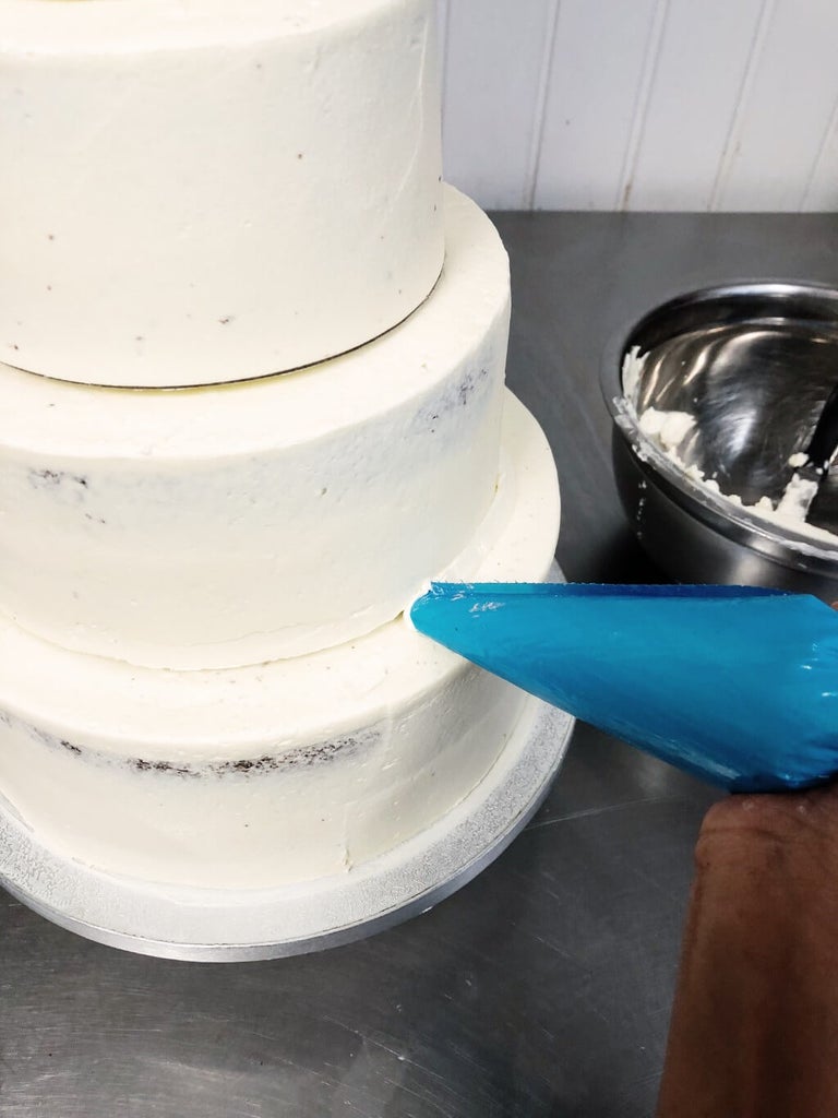 Buttercream tubes on the edges on the base of the cake tiers