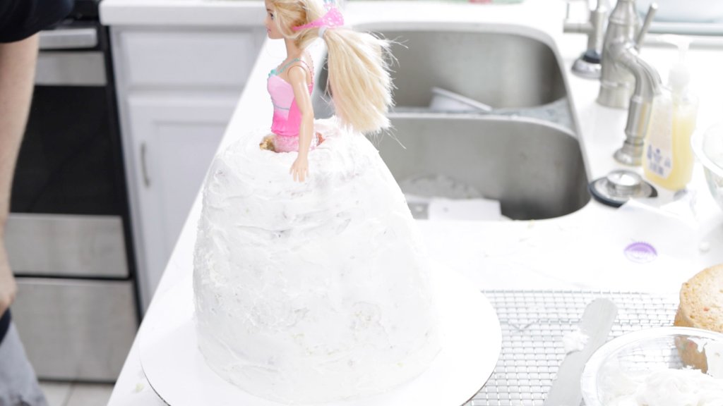 Barbie in a multi-layered cake with white frosting.