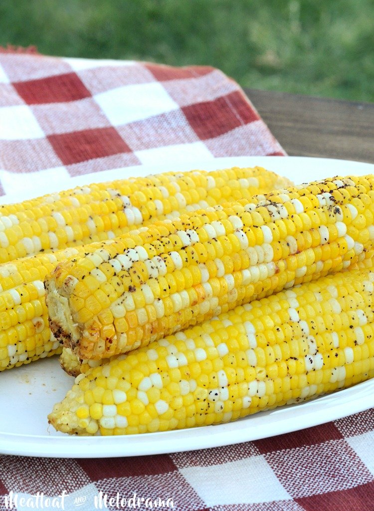 platter of grilled corn in foil on the cob