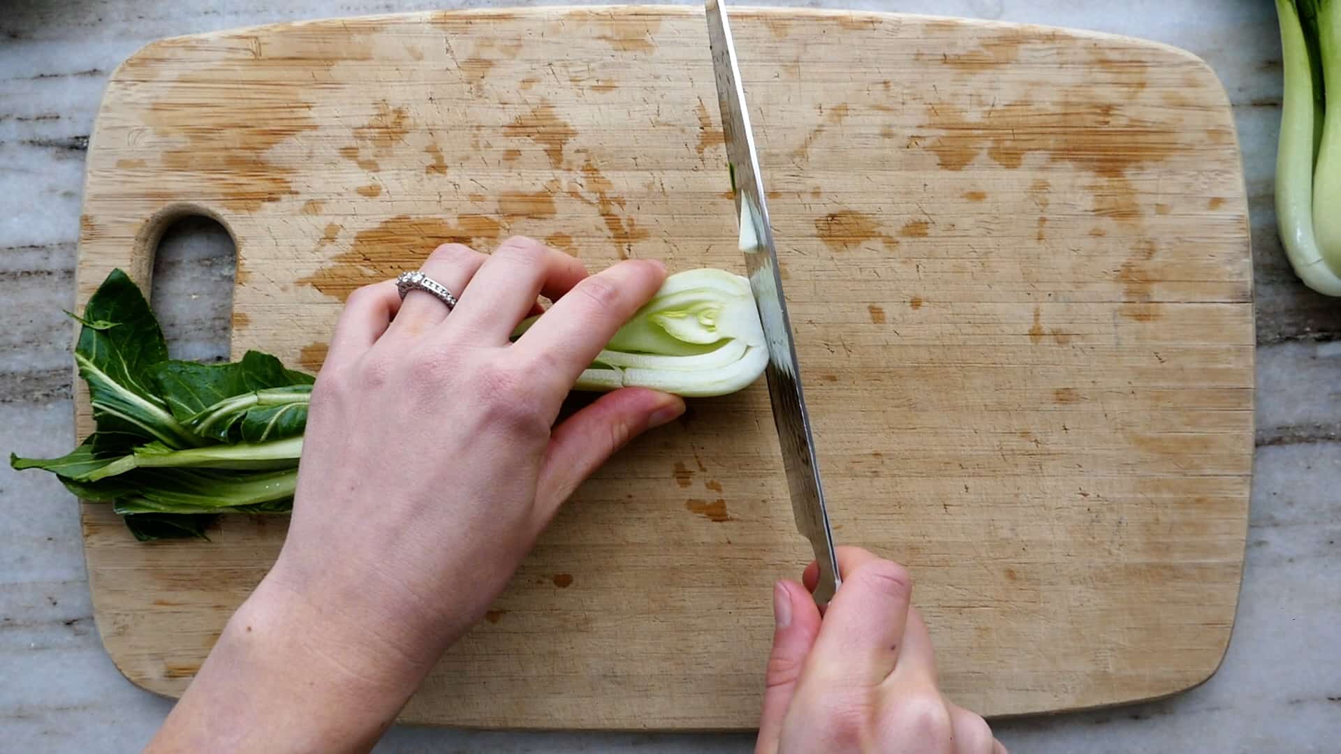 woman cutting off the end of the chopsticks on the cutting board