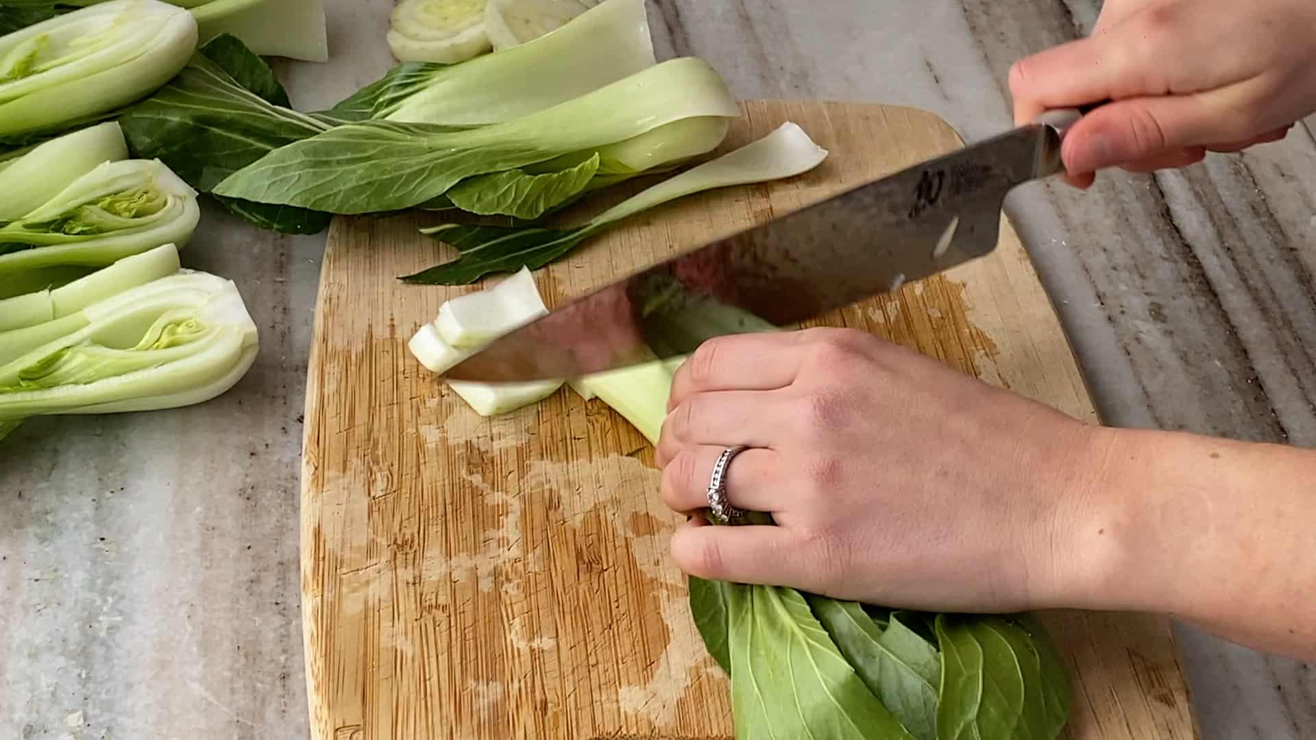 woman chopping cabbage on a bamboo cutting board