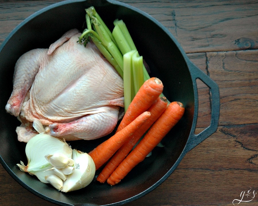 Learn how to boil chicken! Aerial shot of both large chicken and vegetables.