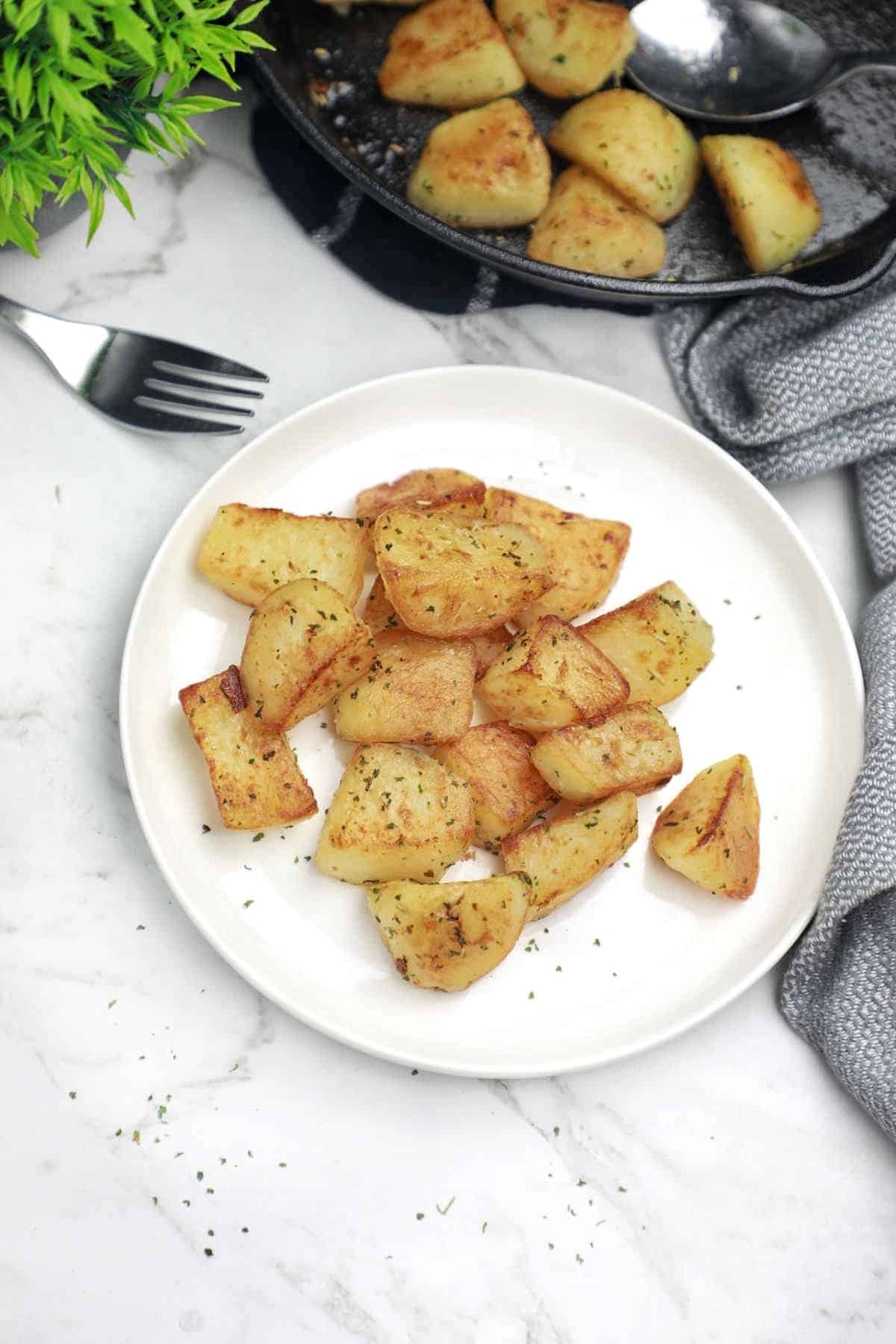 some potatoes on the plate and some in the pan.